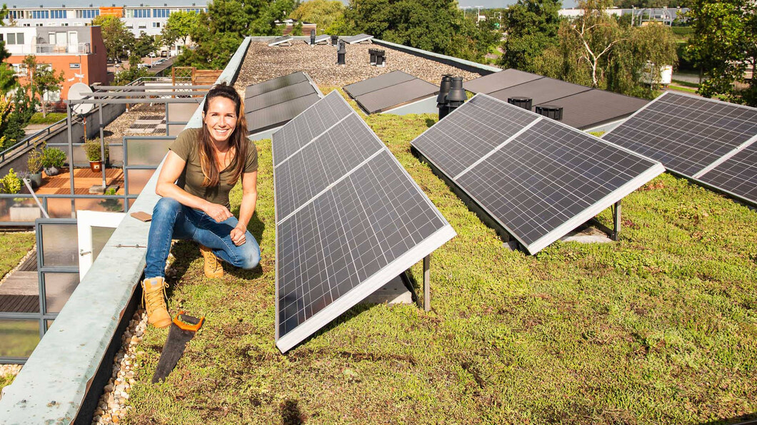 vrouw monteert zonnepanelen op een dak