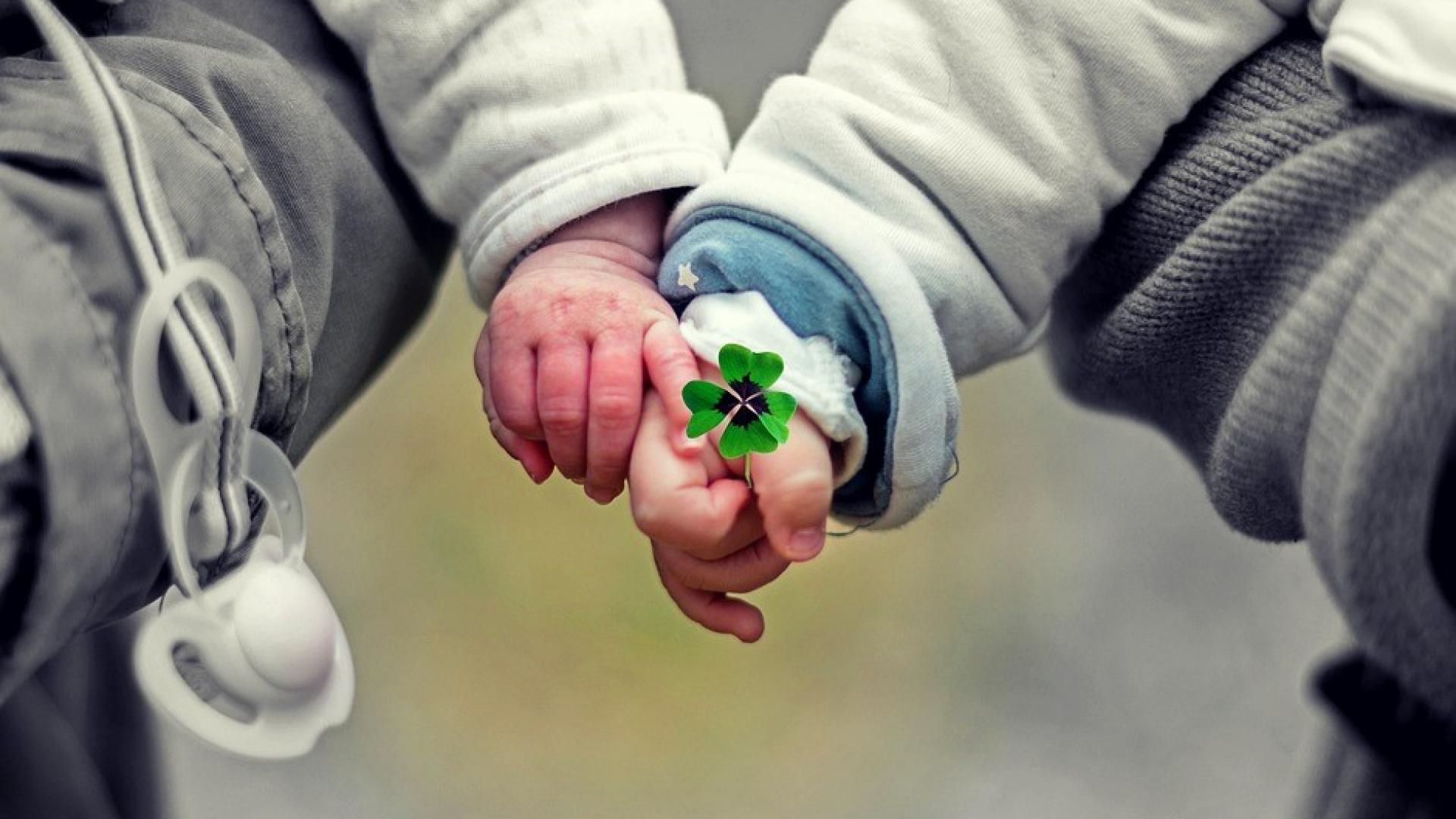 foto twee kinderhanden met een klavertje vier